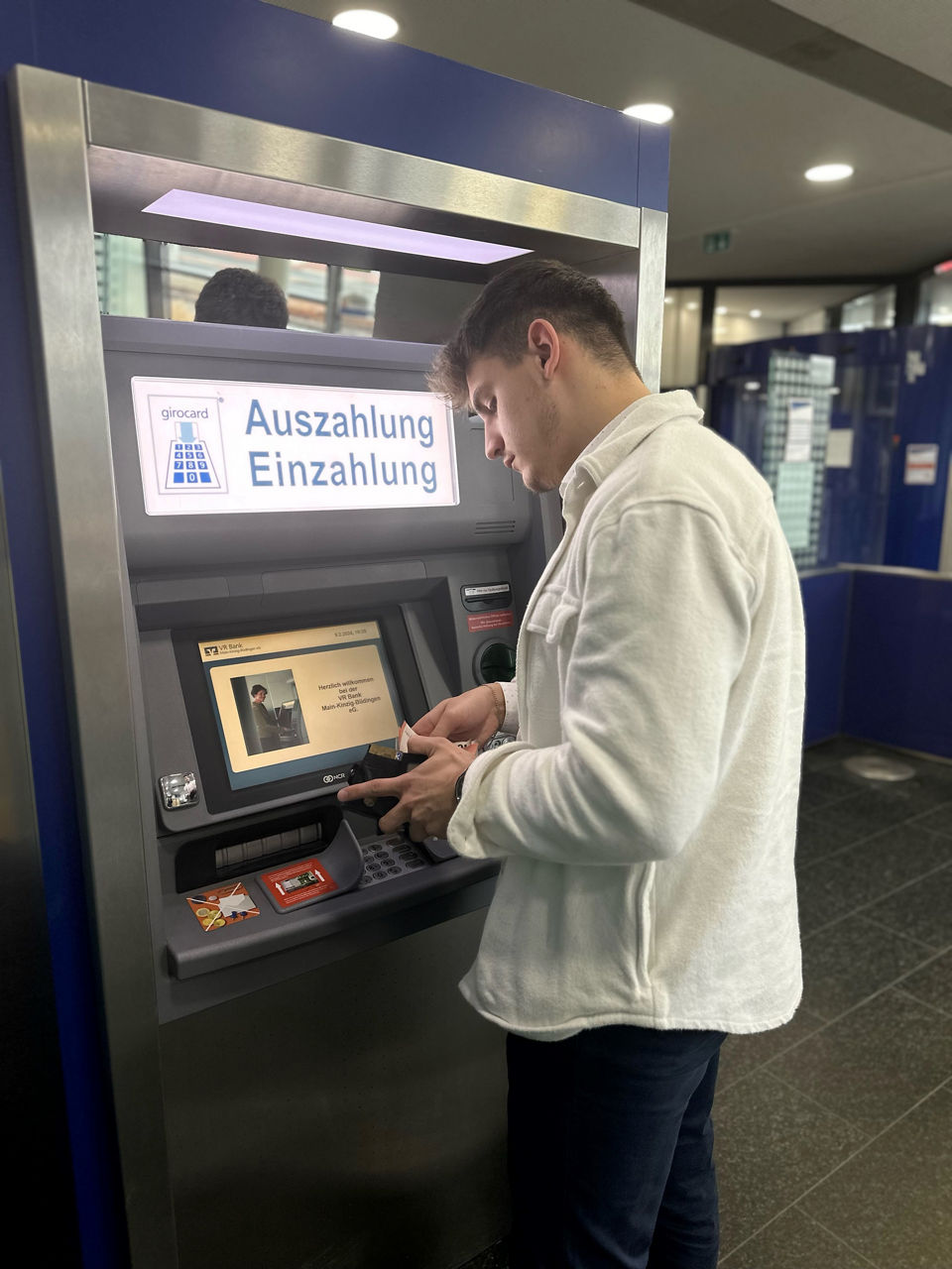 Das Bild zeigt einen Mann, der an einem Geldautomat Bargeld abhebt.