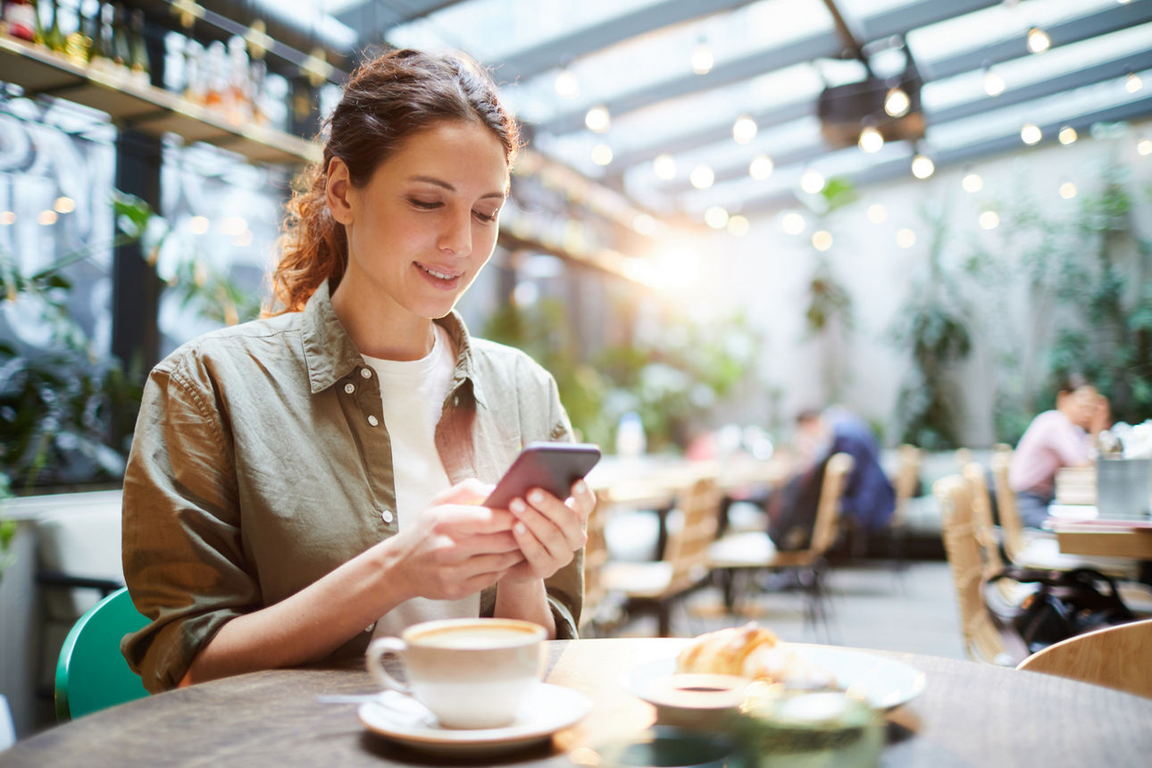 Frau im Cafe mit Handy in der Hand