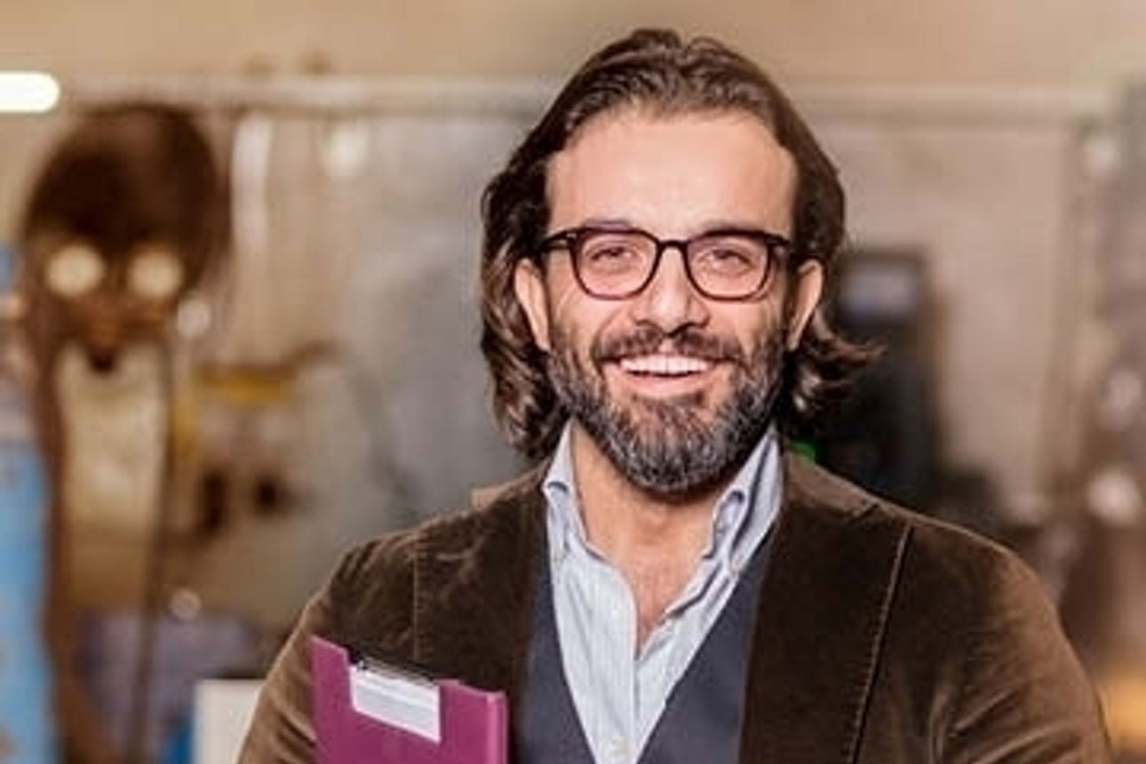 Ein Mann mit Brille und Bart hält eine Mappe in der Hand und sieht konzentriert und engagiert bei der Arbeit aus.