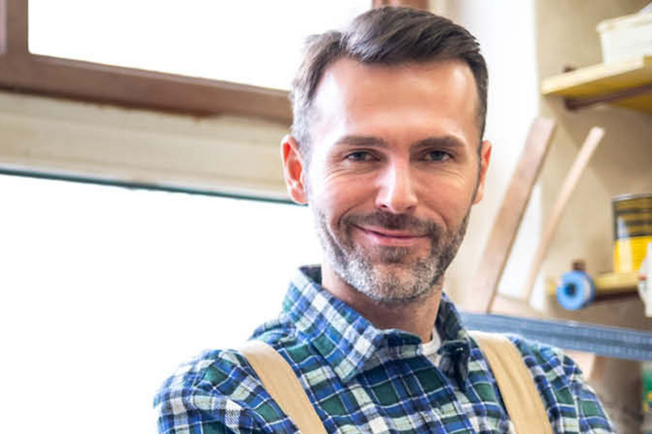 Handwerker vor Fenster in seiner Werkstatt