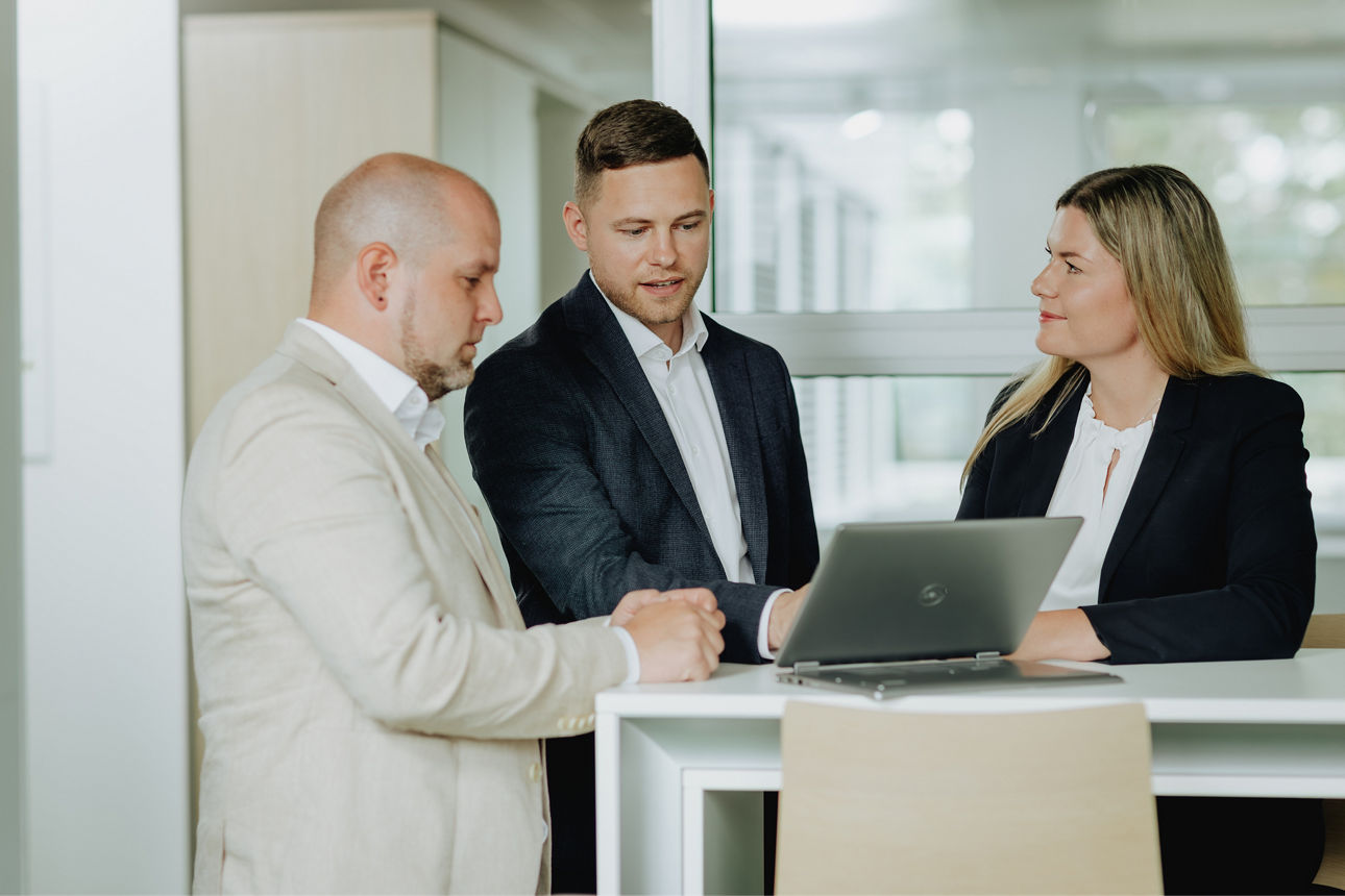 Ein Geschäftsmann schaut mit Beraterin und Berater ins Online-Banking