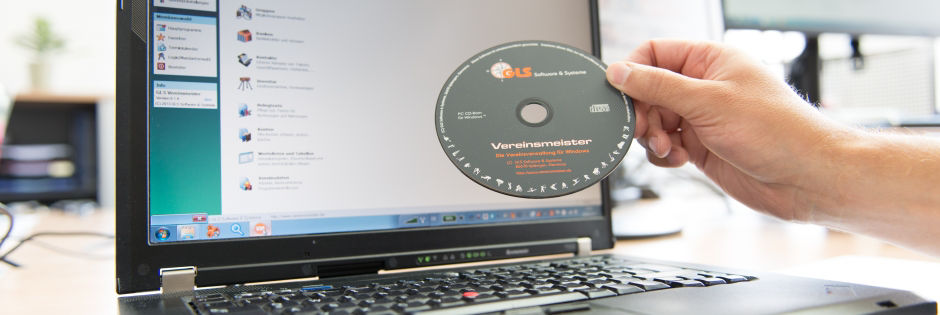 Hand hält CD vor Laptop