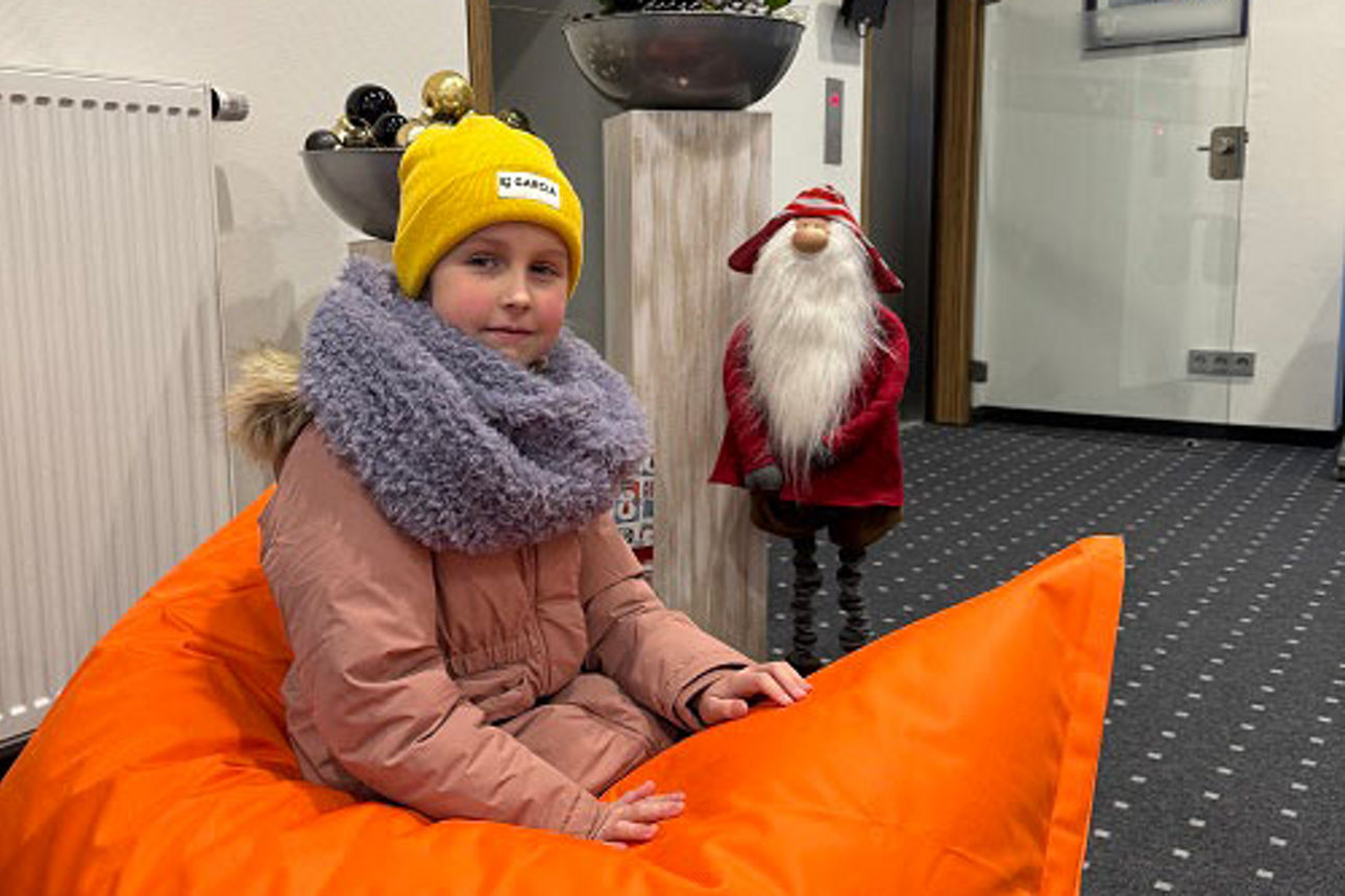 Ein Mädchen auf einem organgenen Sitzkissen. 