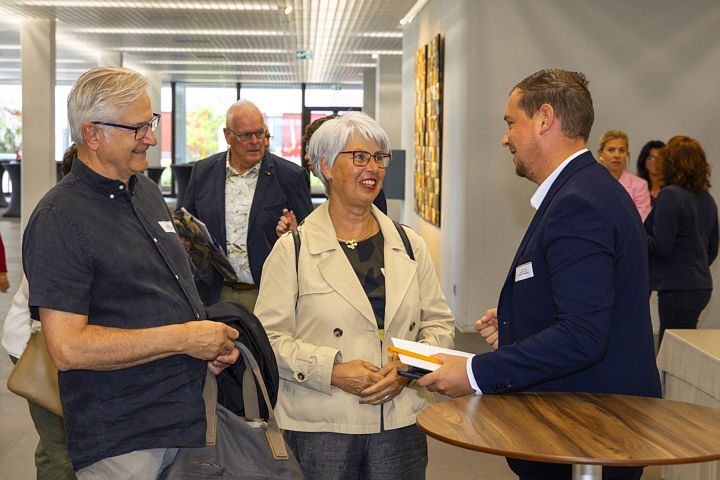 Gewinnerin mit Ehemann und Bankmitarbeiter im Gespräch