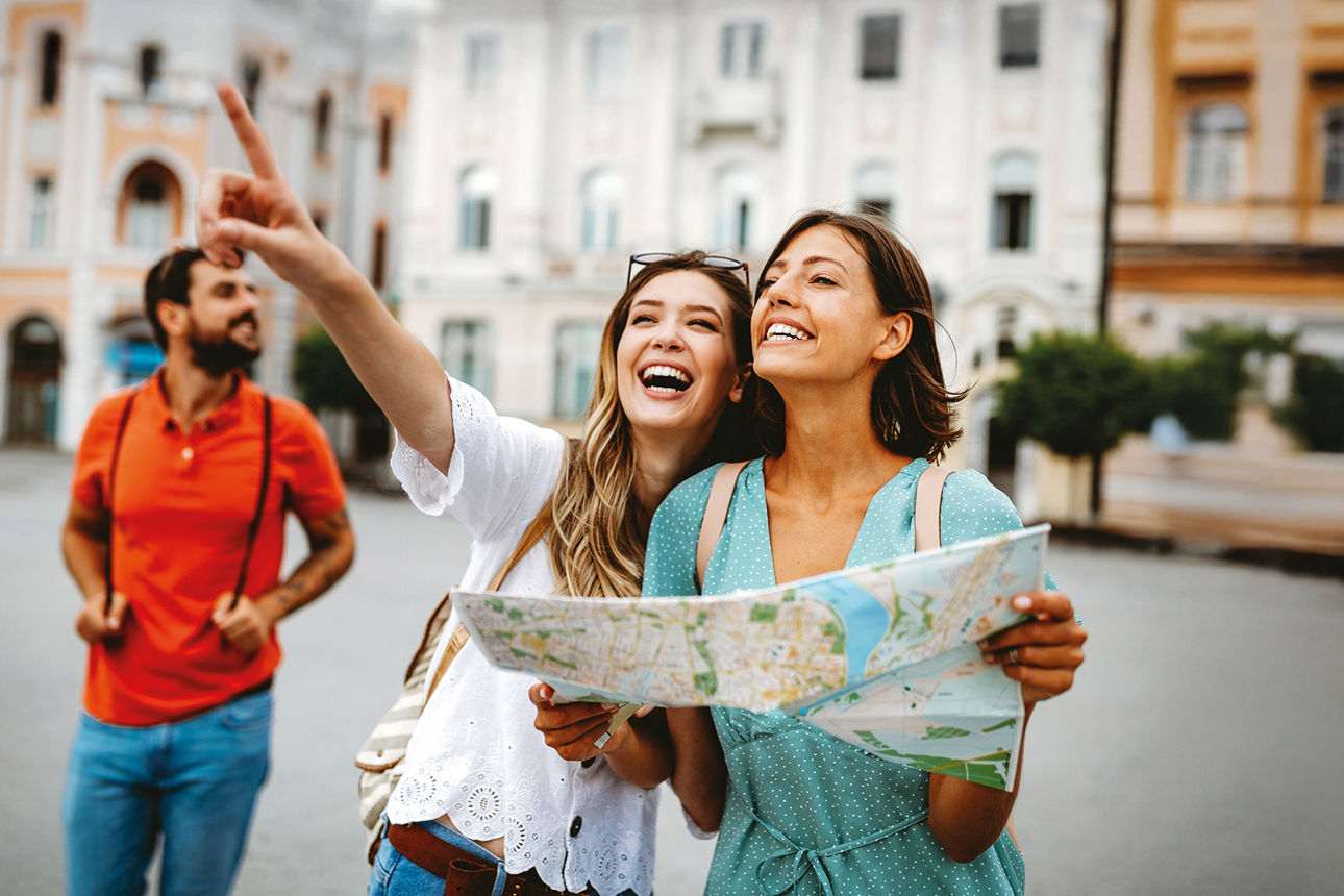 Glückliche Touristinnen beim Sightseeing mit Karte in der Hand