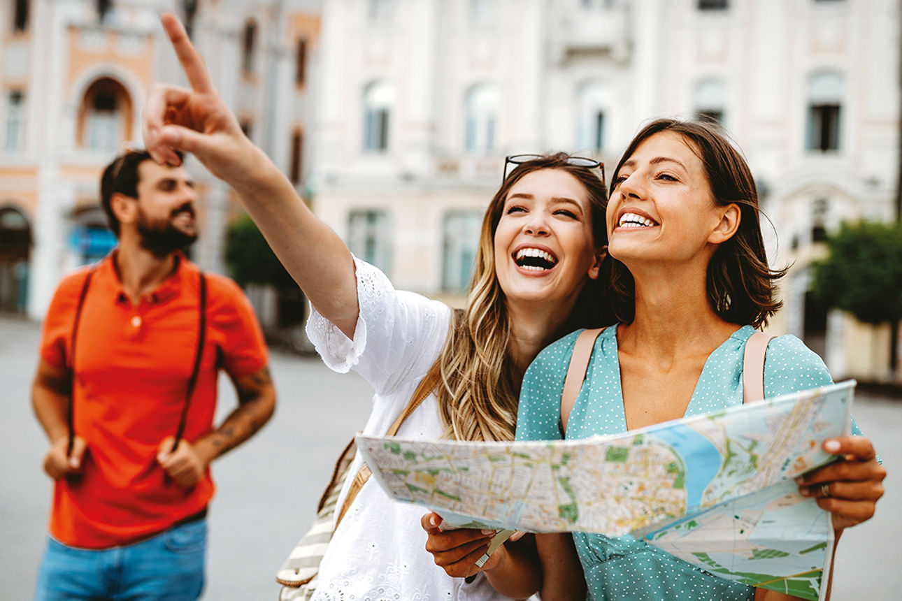 Happy traveling women tourists sightseeing with map in hand