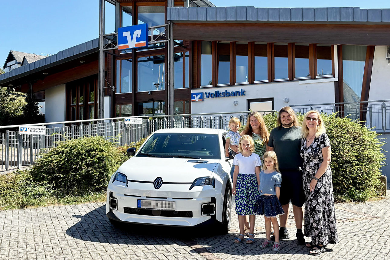 Ulrike Emmel, Gewerbekundenberaterin der Volksbank Rhein-Lahn-Limburg eG (rechts), gratuliert herzlich einer jungen Familie zu einem neuen E-Auto. 