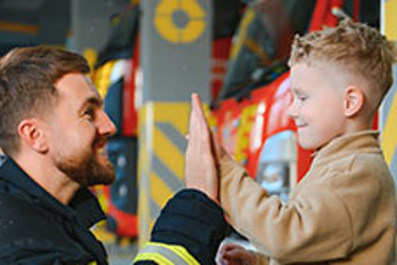 Feuerwehrmann und kleiner Junge machen Handschlag