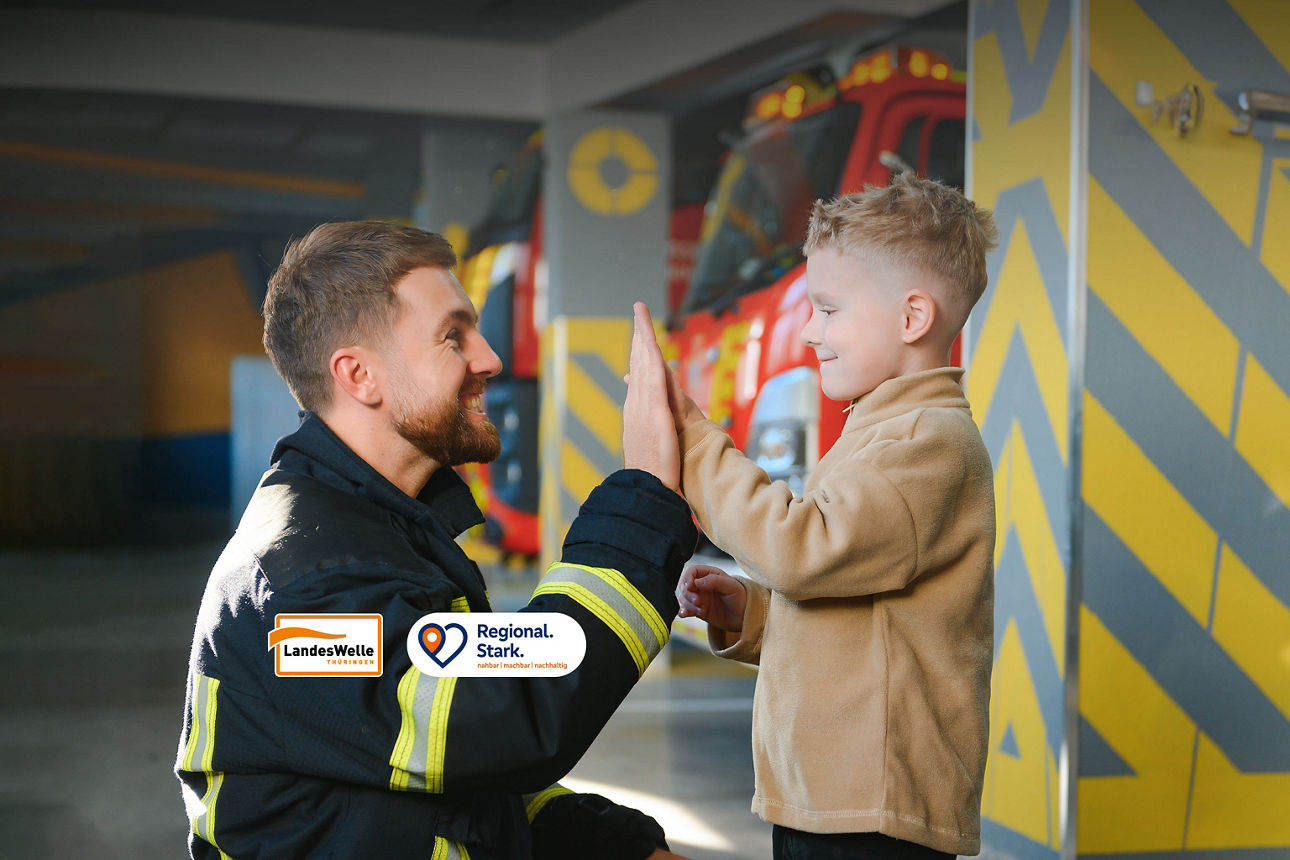 Feuerwehrmann und Junge klatschen sich ab.