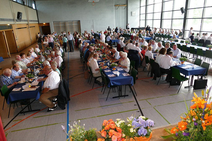 eine große Gruppe von Menschen, die an den Tischen feiern