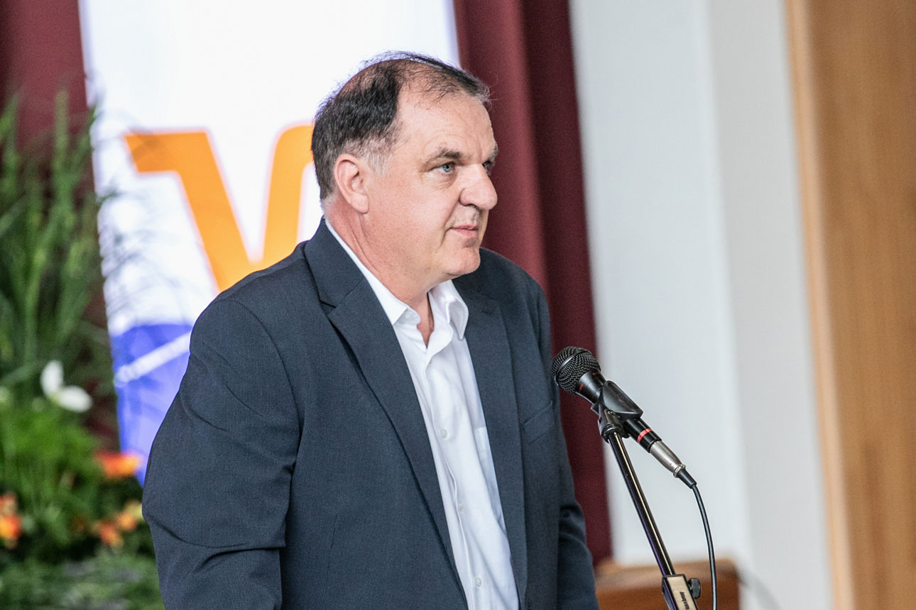 Mann im Anzug steht an einem Rednerpult und hält eine Rede auf der Generalversammlung