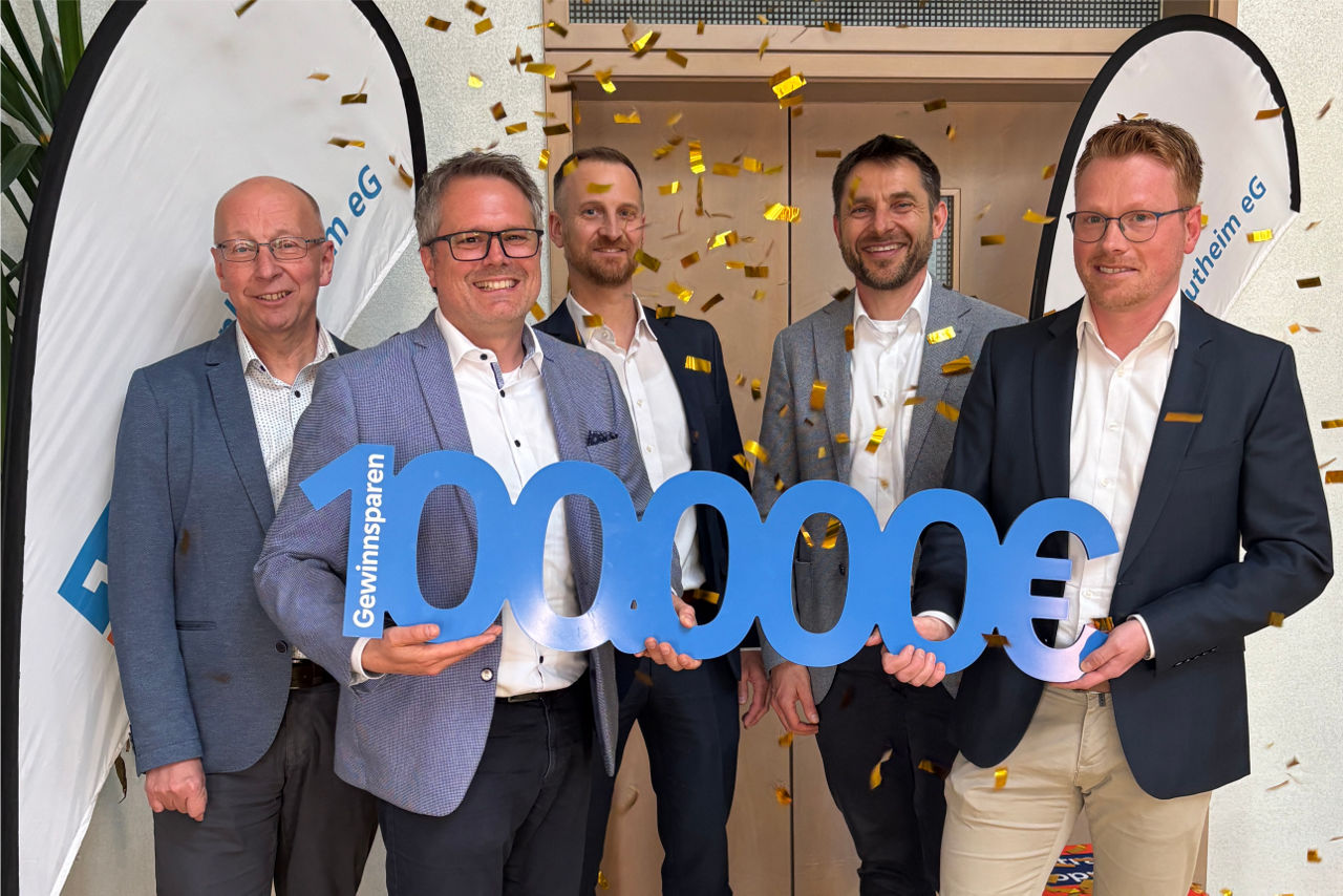 Fünf lachende Männer mit 100.000 Euro-Schild in der Hand
