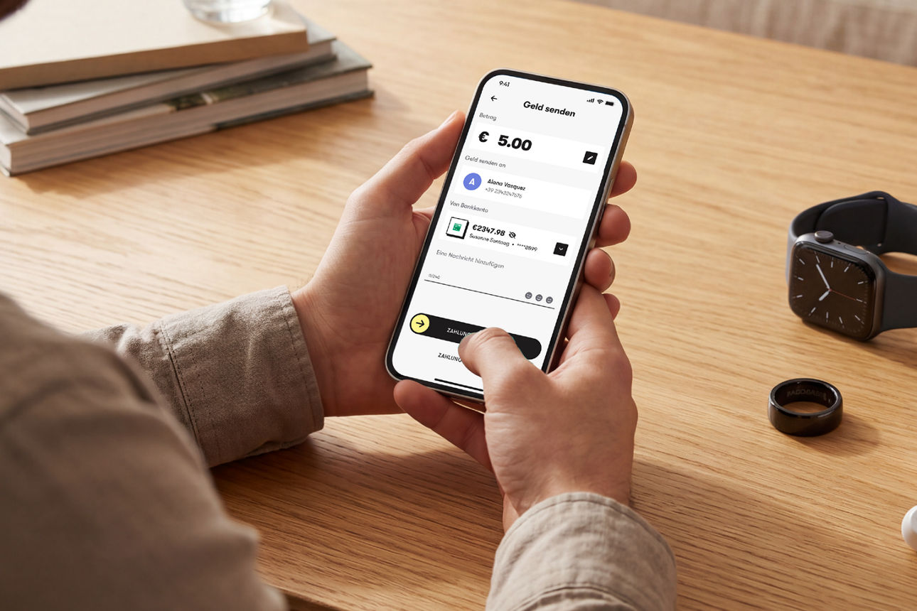 Mann hält sein Smartphone am Wohnzimmertisch