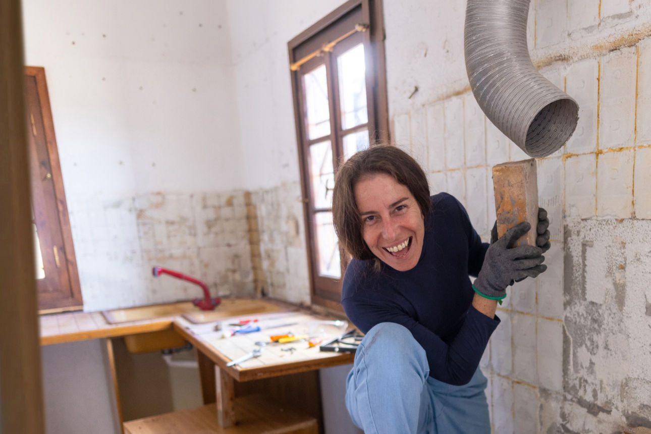 Frau mit Ziegelstein in der Hand beim Renovieren 