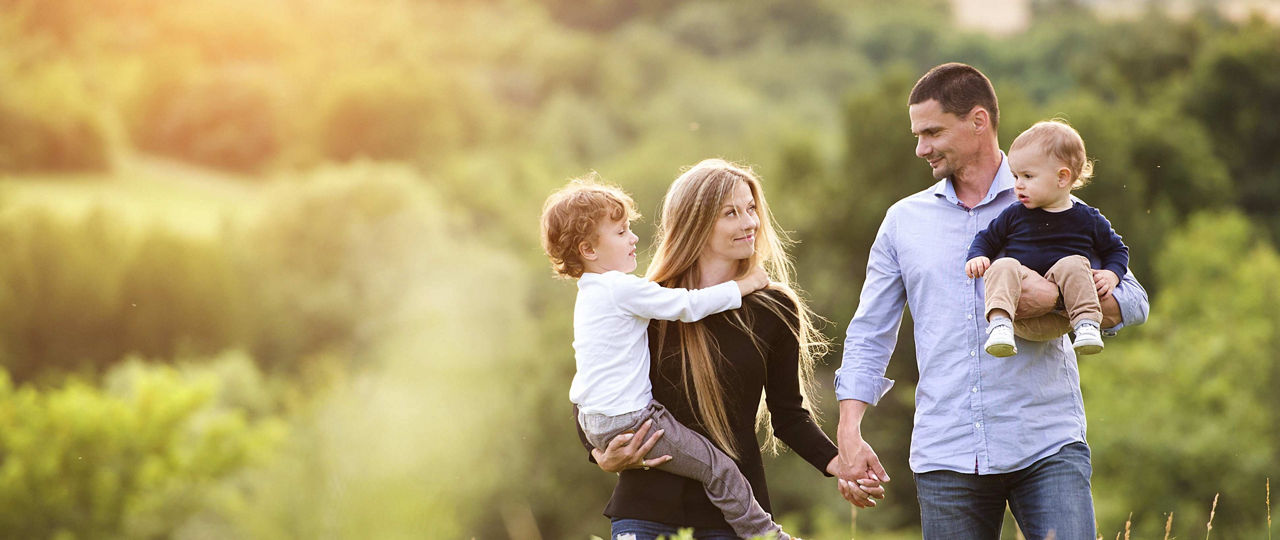 Junge Familie geht auf Feld im Sonnenschein spazieren