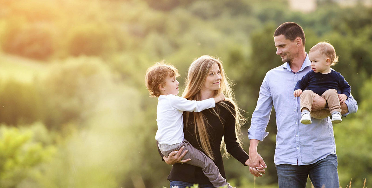 Junge Familie geht auf Feld im Sonnenschein spazieren
