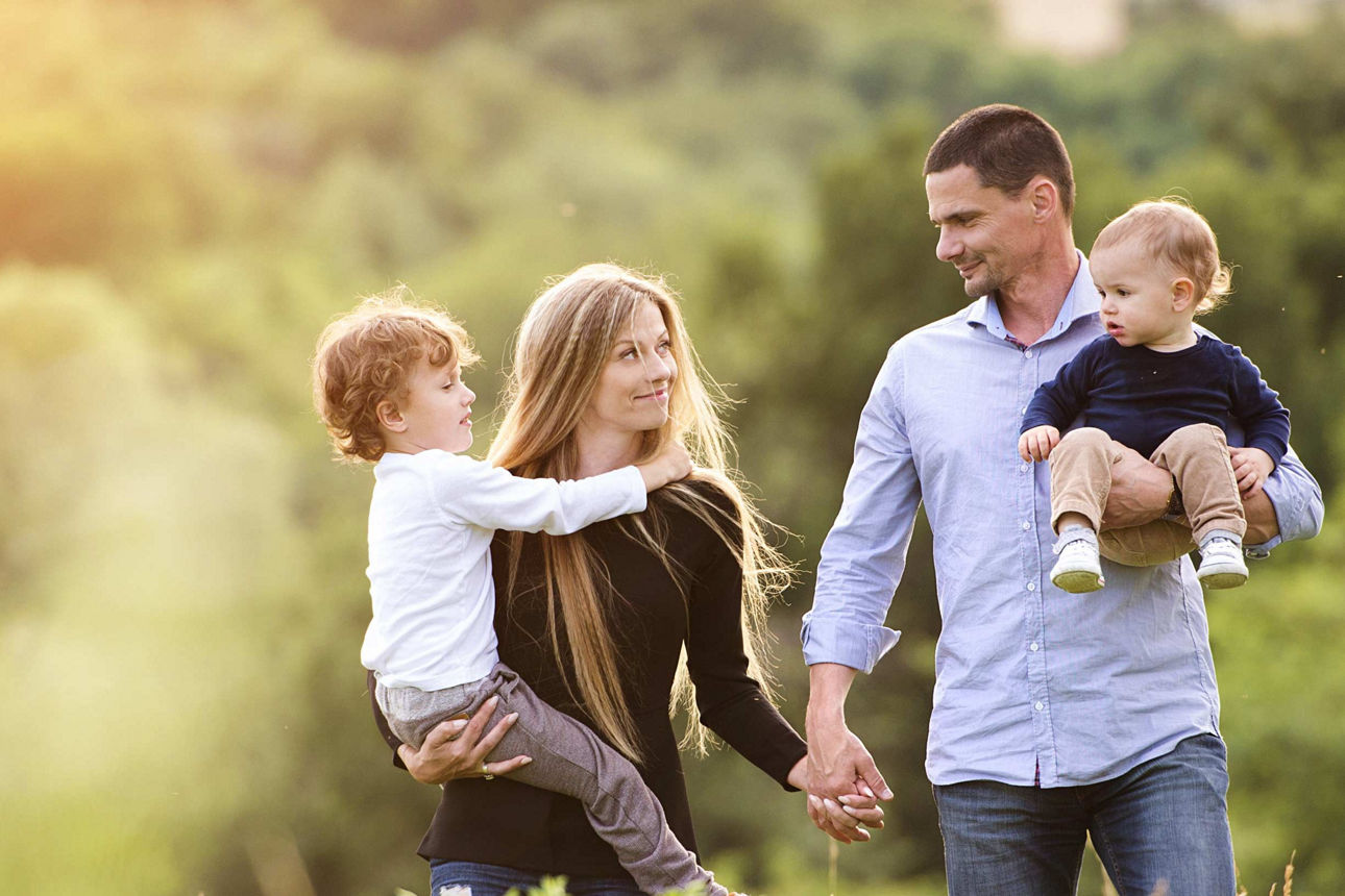 Junge Familie geht auf Feld im Sonnenschein spazieren