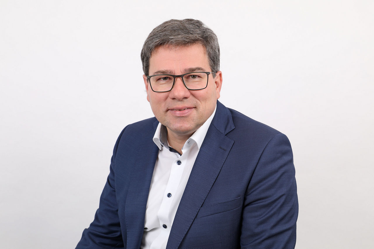 Mitarbeiter, Robert Gehringer, vor weißem Hintergrund lächelt in die Kamera