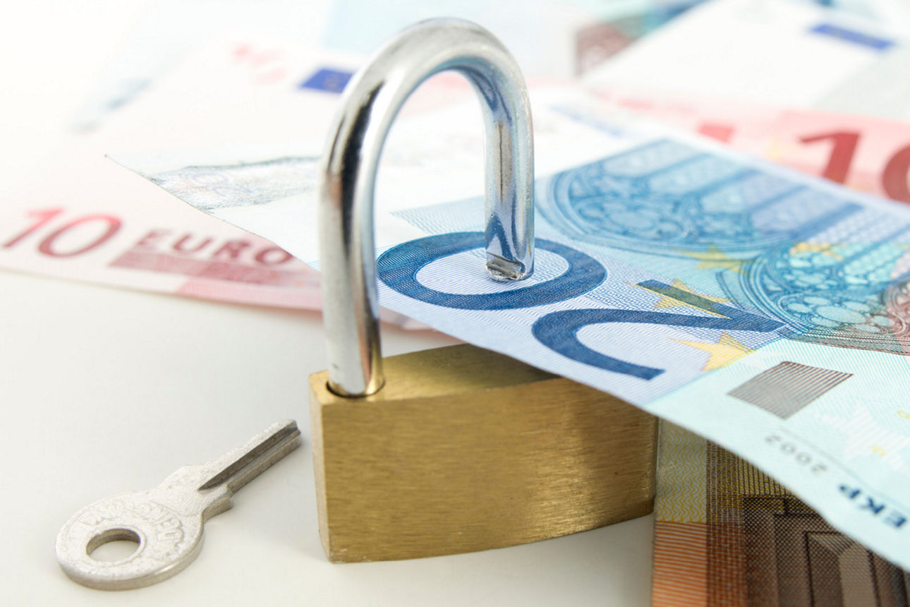 In ein geöffnetes Vorhängeschloss sind Geldscheine eingelegt