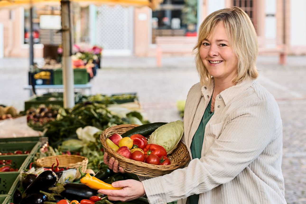 Frau mit Obstkorb vor Marktstand