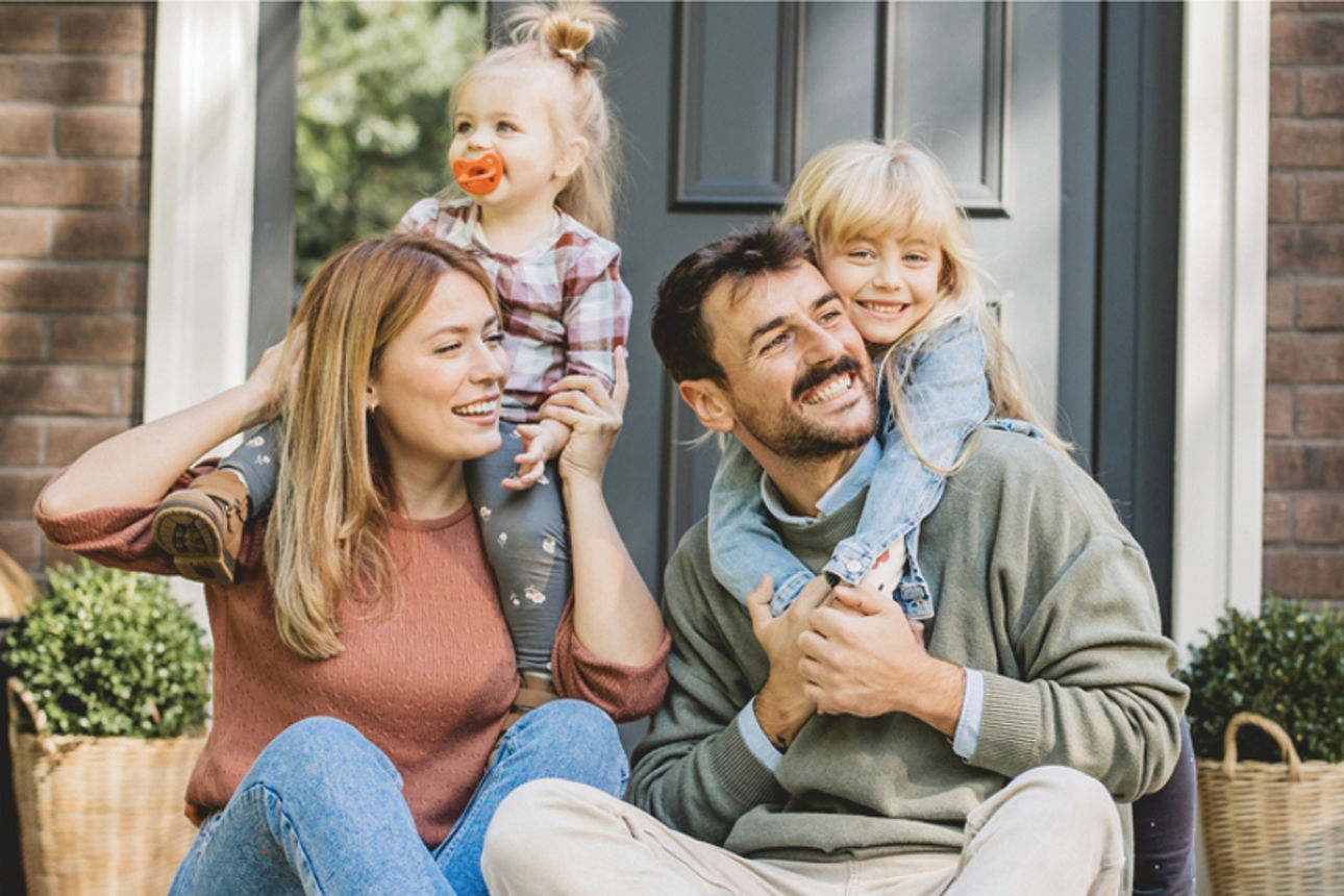 Familie sitzt vor dem Haus
