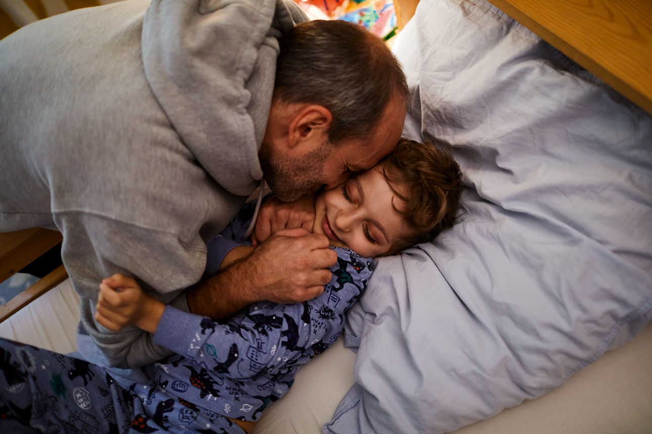 Ein Vater kuschelt mit seinem Sohn.