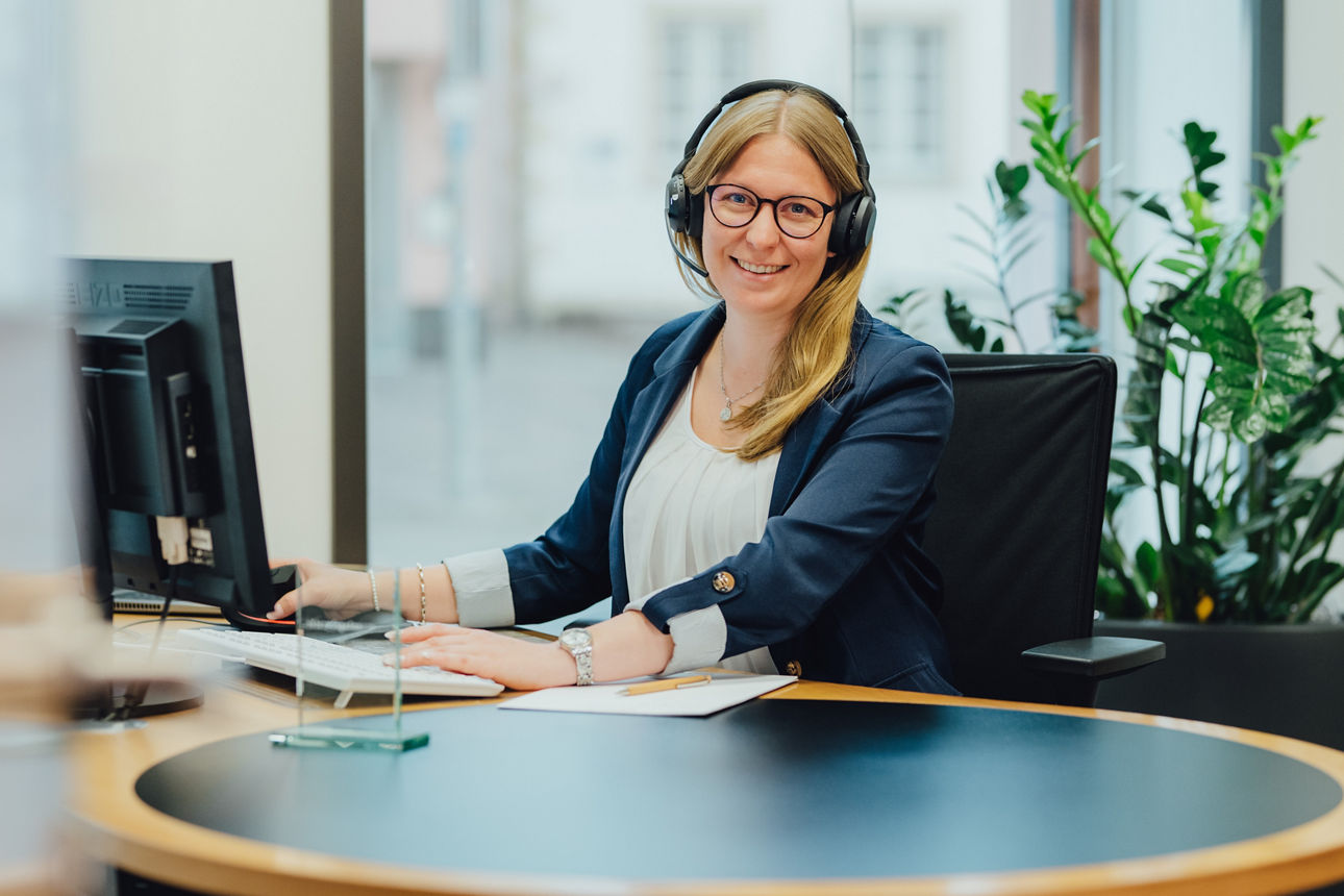 Frau mit Headset lacht in die Kamera
