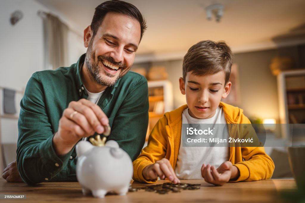 Father and son save money coins together at piggy bank at home