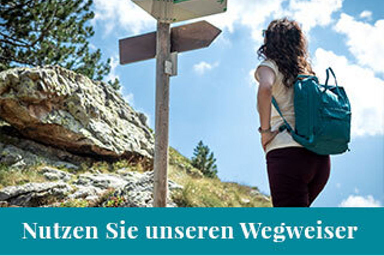 Frau beim Wandern vor Wegweiser 