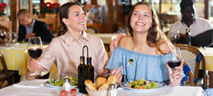 Zwei Frauen sitzen an einem Tisch und trinken Wein 
