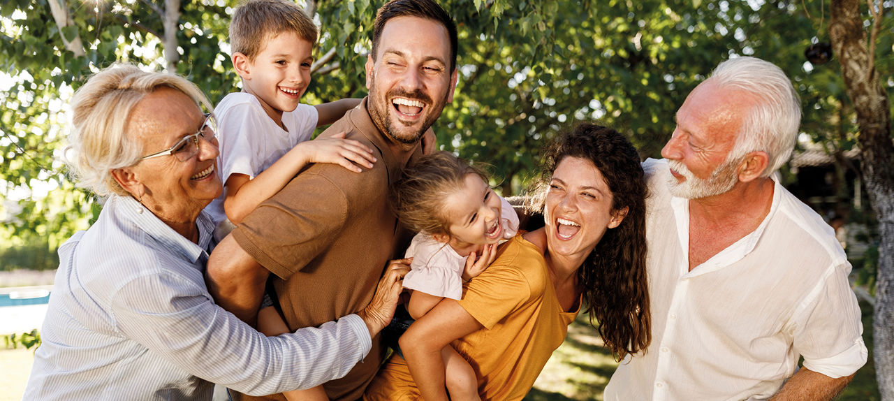Mehrgenerationen-Familie lacht zusammen im Garten