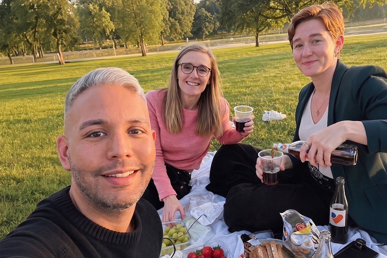 Ein Mann und zwei Frauen bei einem Picknick auf einer Wiese