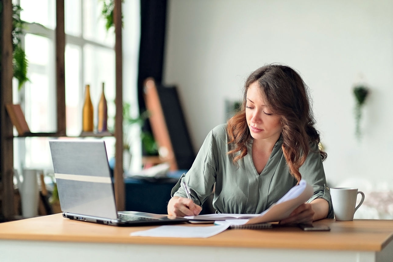 Young woman working from home office. Freelancer using laptop and the Internet. Workplace in living room