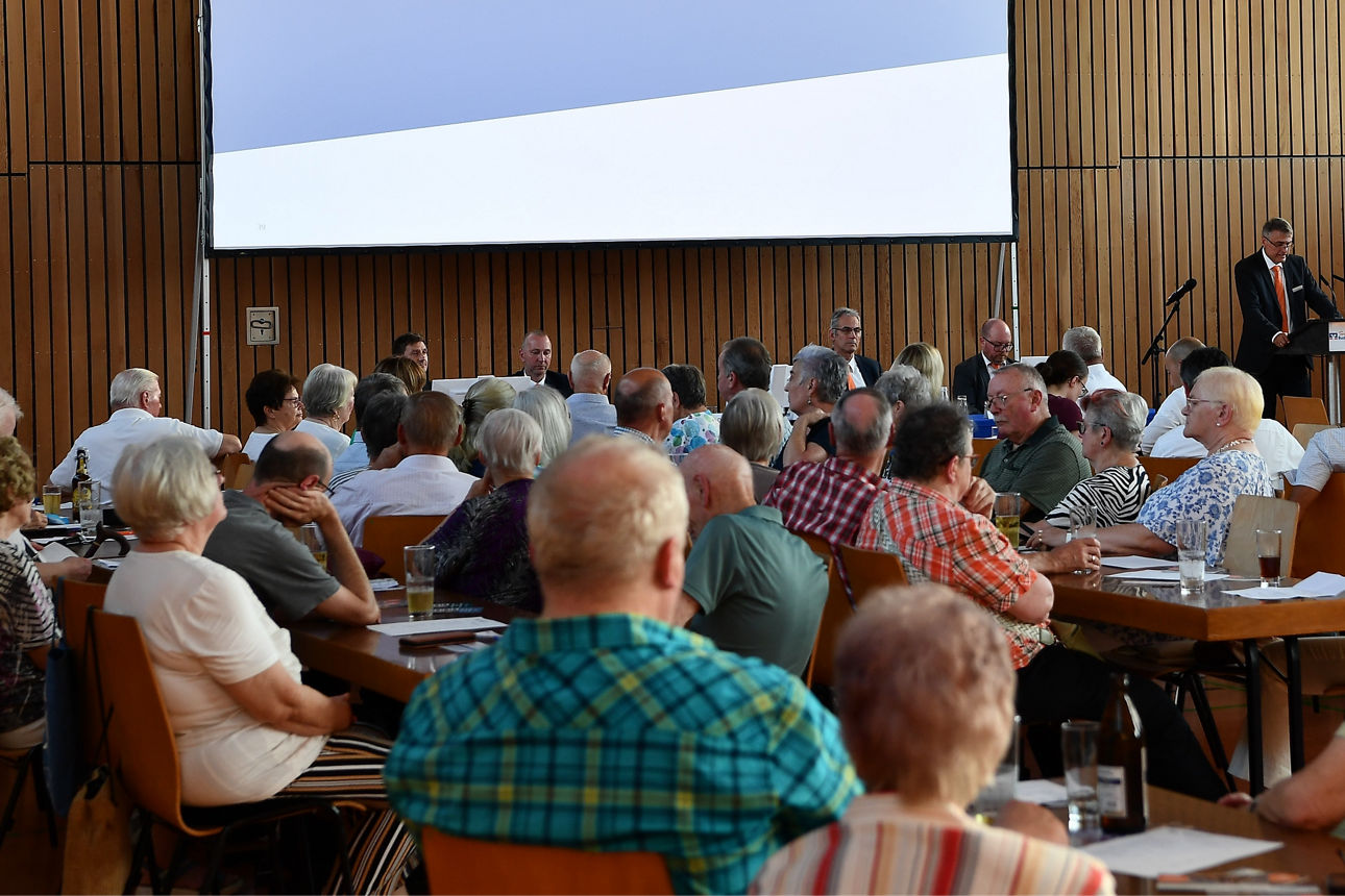Projektionsleinwand, auf der ein Tagesordnungspunkt mit dem Titel „Bericht des Aufsichtsrats“ angezeigt wird.