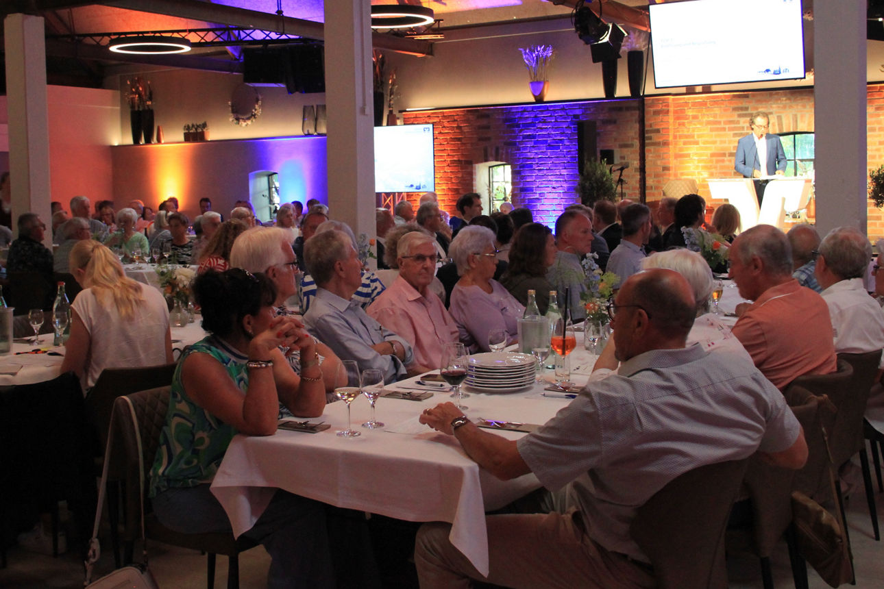 Viele Menschen auf einer Generalversammlung, gut gekleidet und an den Tischen sitzend