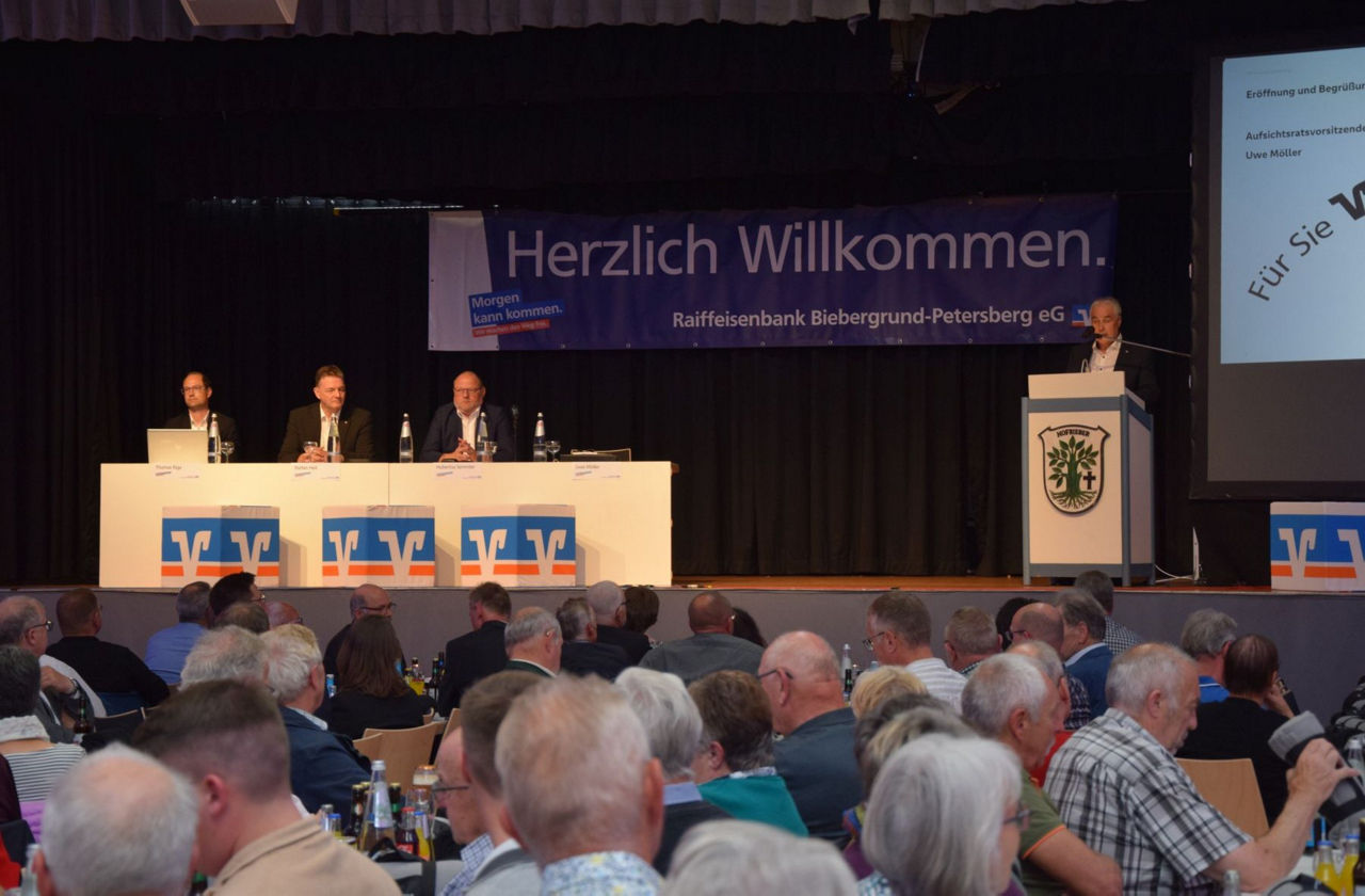 Eine Bühne mit dem Volksbank Logo und vier Herren.