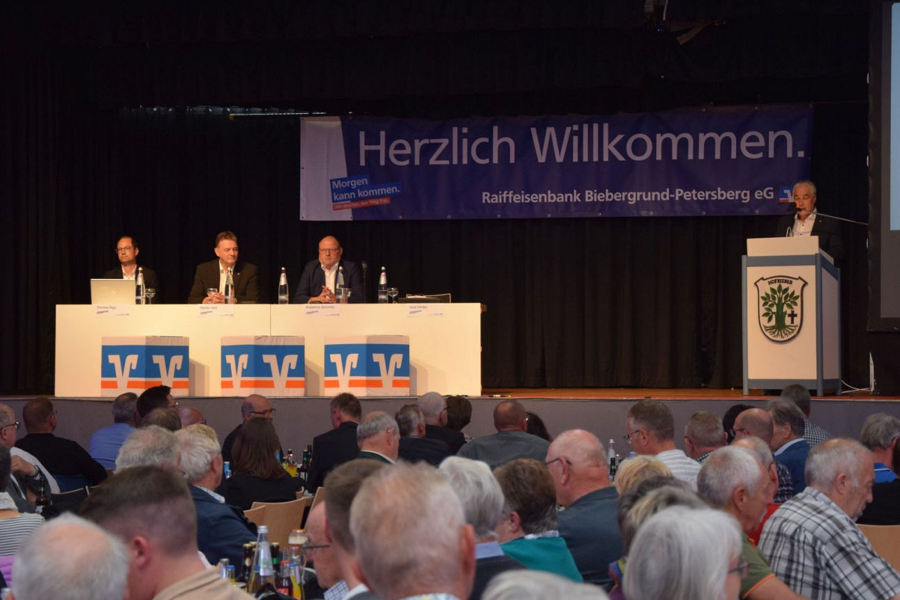 Eine Bühne mit dem Volksbank Logo und vier Herren.