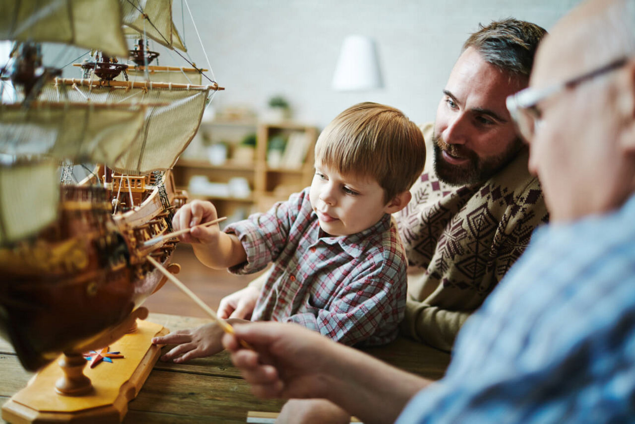 Drei Generationen arbeiten an einem Modellboot.