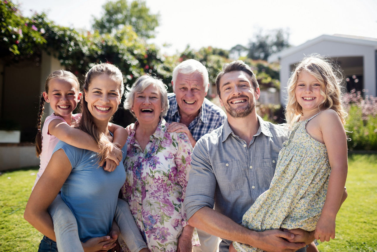 Porträt einer Mehrgenerationenfamilie im Garten an einem sonnigen Tag