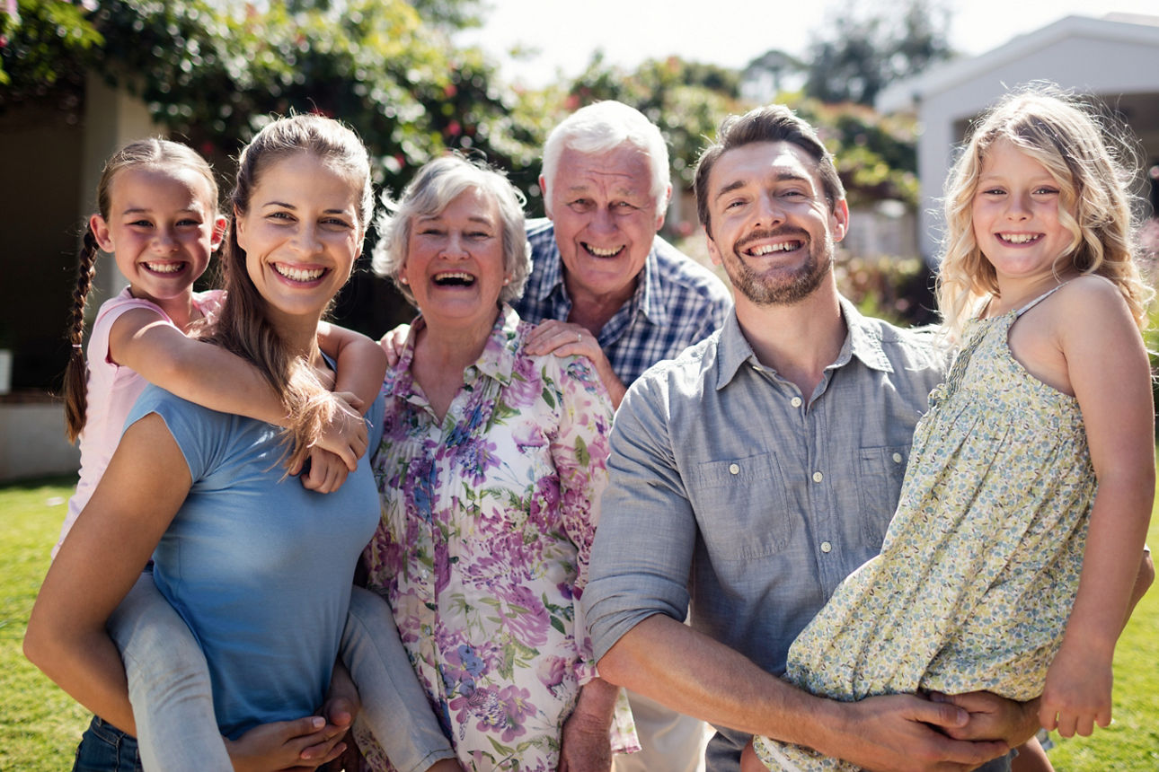 Porträt einer Mehrgenerationenfamilie im Garten an einem sonnigen Tag