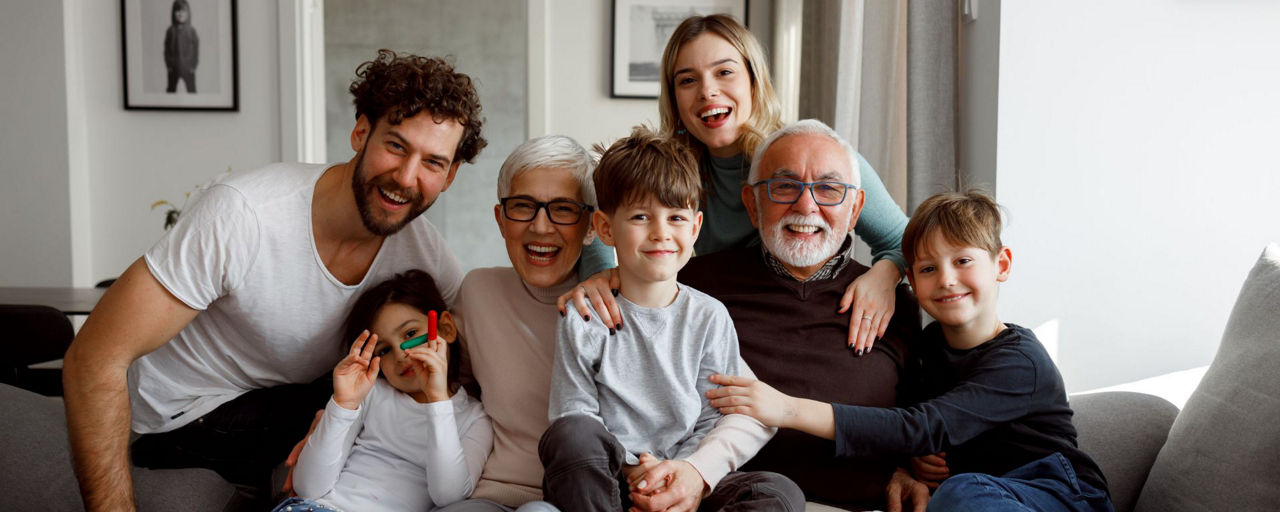 7 Familienmitglieder aus 3 Generationen sitzen freudestrahlend auf der Couch