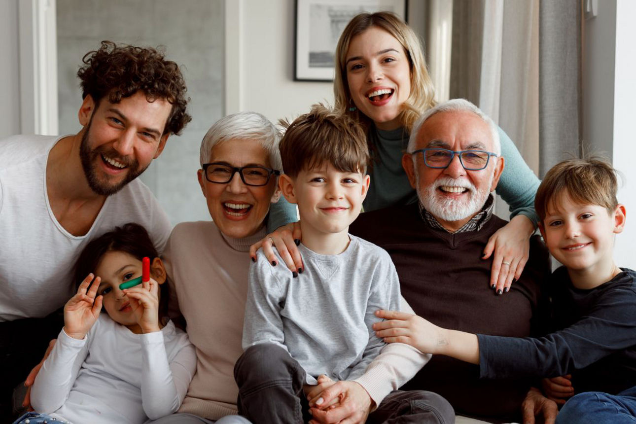 7 Familienmitglieder aus 3 Generationen sitzen freudestrahlend auf der Couch