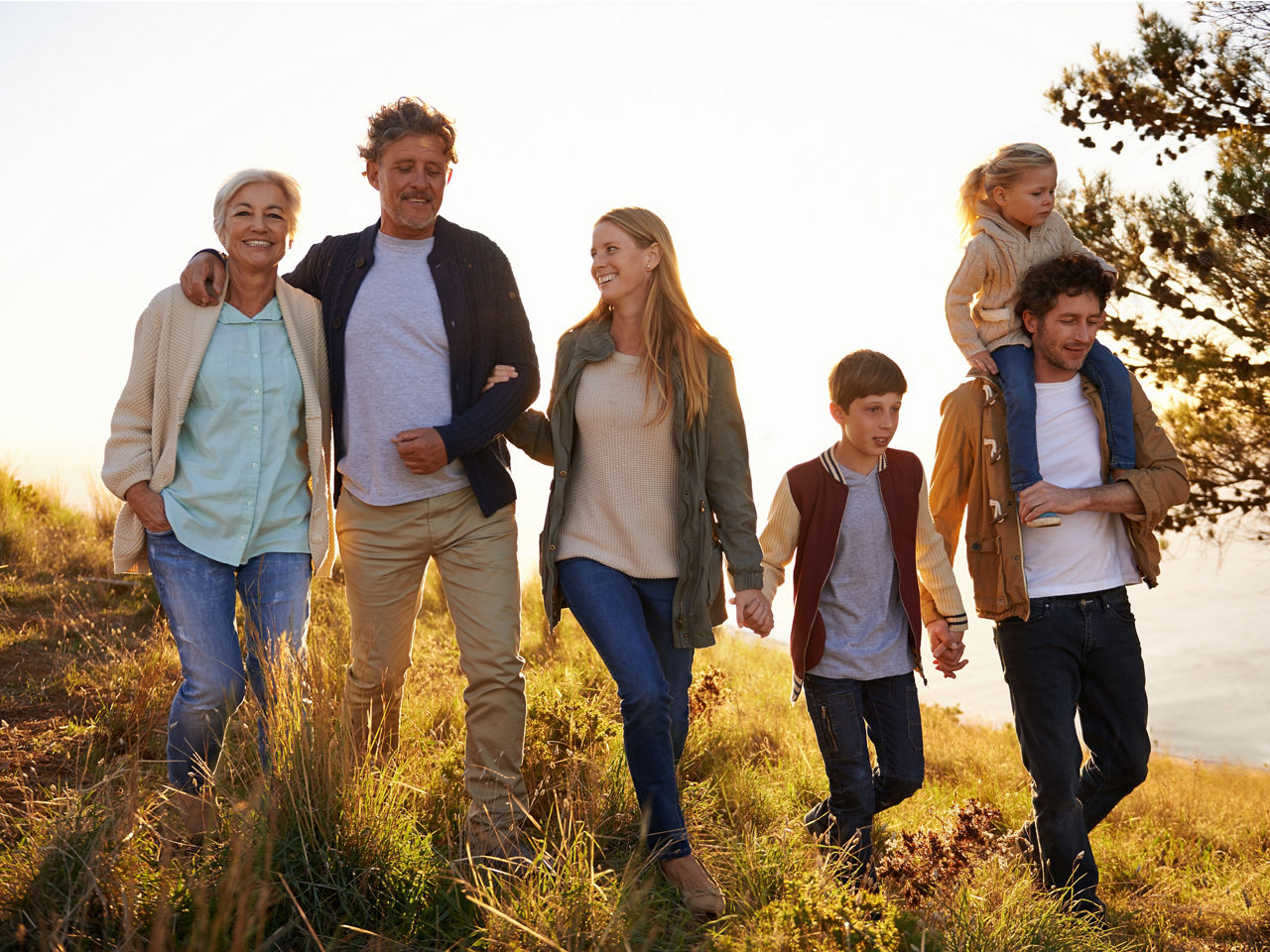 Familie aus mehreren Generationen laufen händchenhaltend auf einer Wiese im Herbst