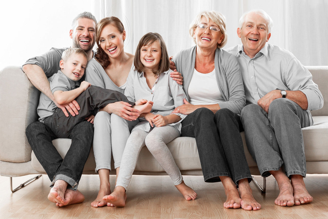 Junge und alte Menschen sitzen auf einer Couch
