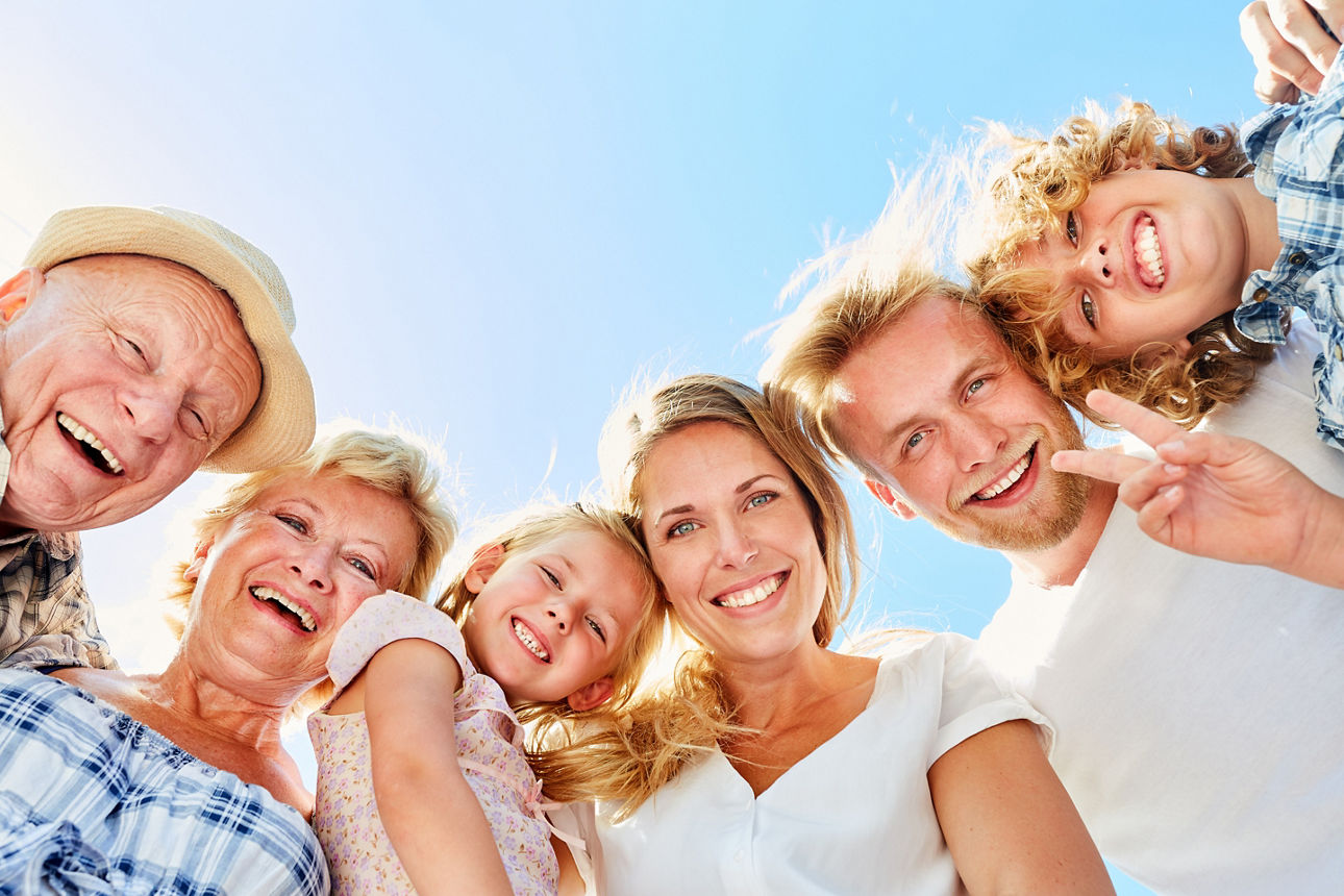 Eine strahlende Familie mit drei Generationen unter blauem Himmel