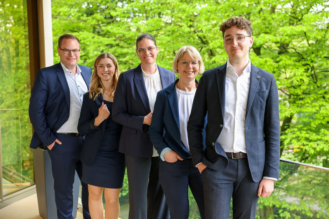 Das Team Generationenmanagement steht vor einem blühenden Baum