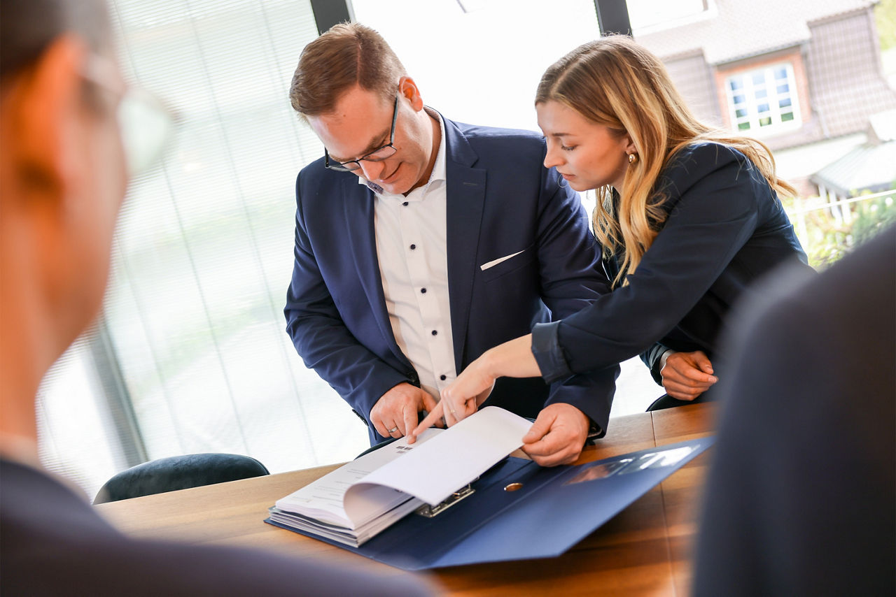Zwei Personen aus dem Team "Finanzplanung und Nachfolgeplanung" stehen an einem Stehtisch und blicken in Dokumente
