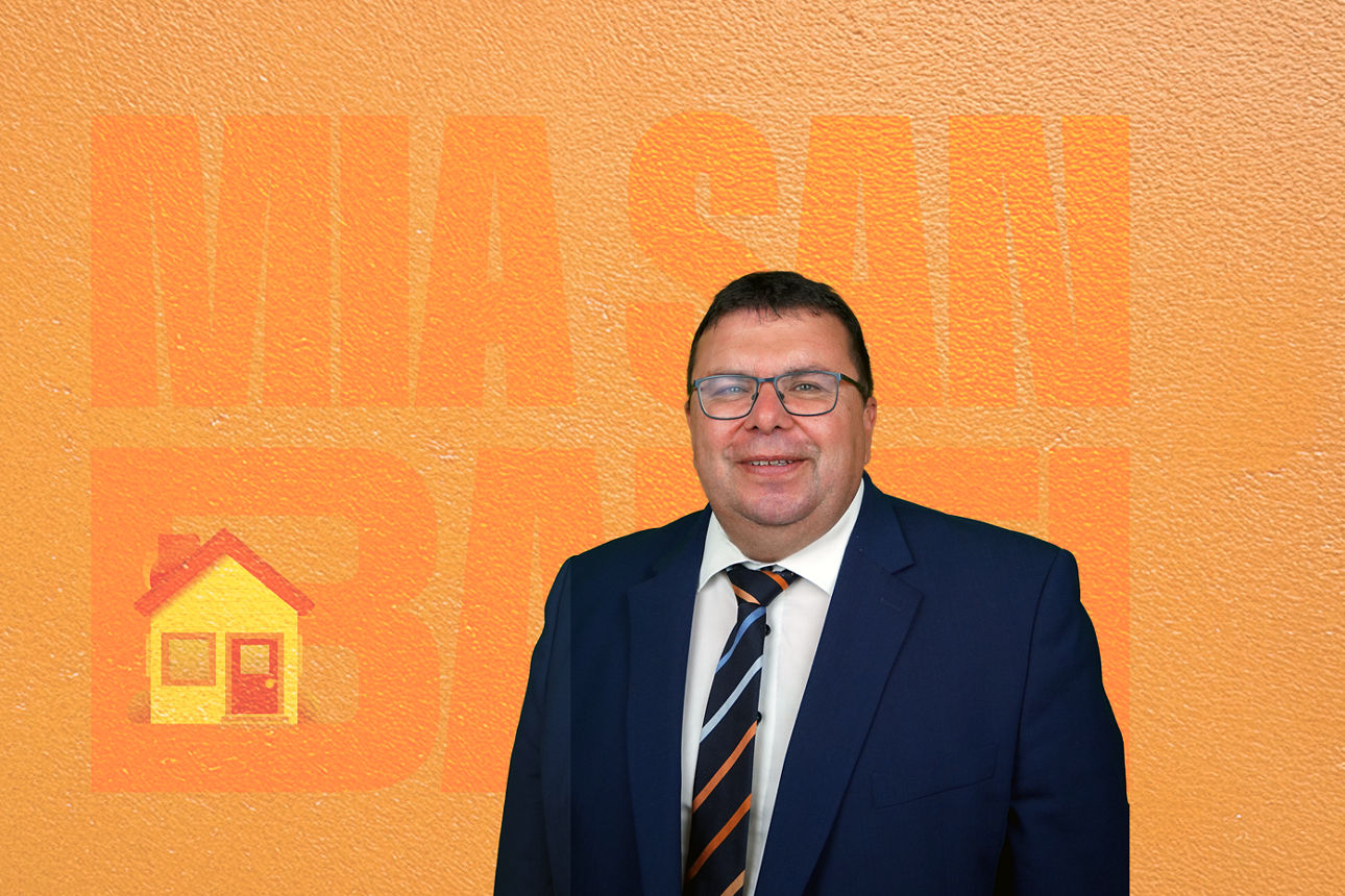 Ein Mann steht vor einem orangen Hintergrund.