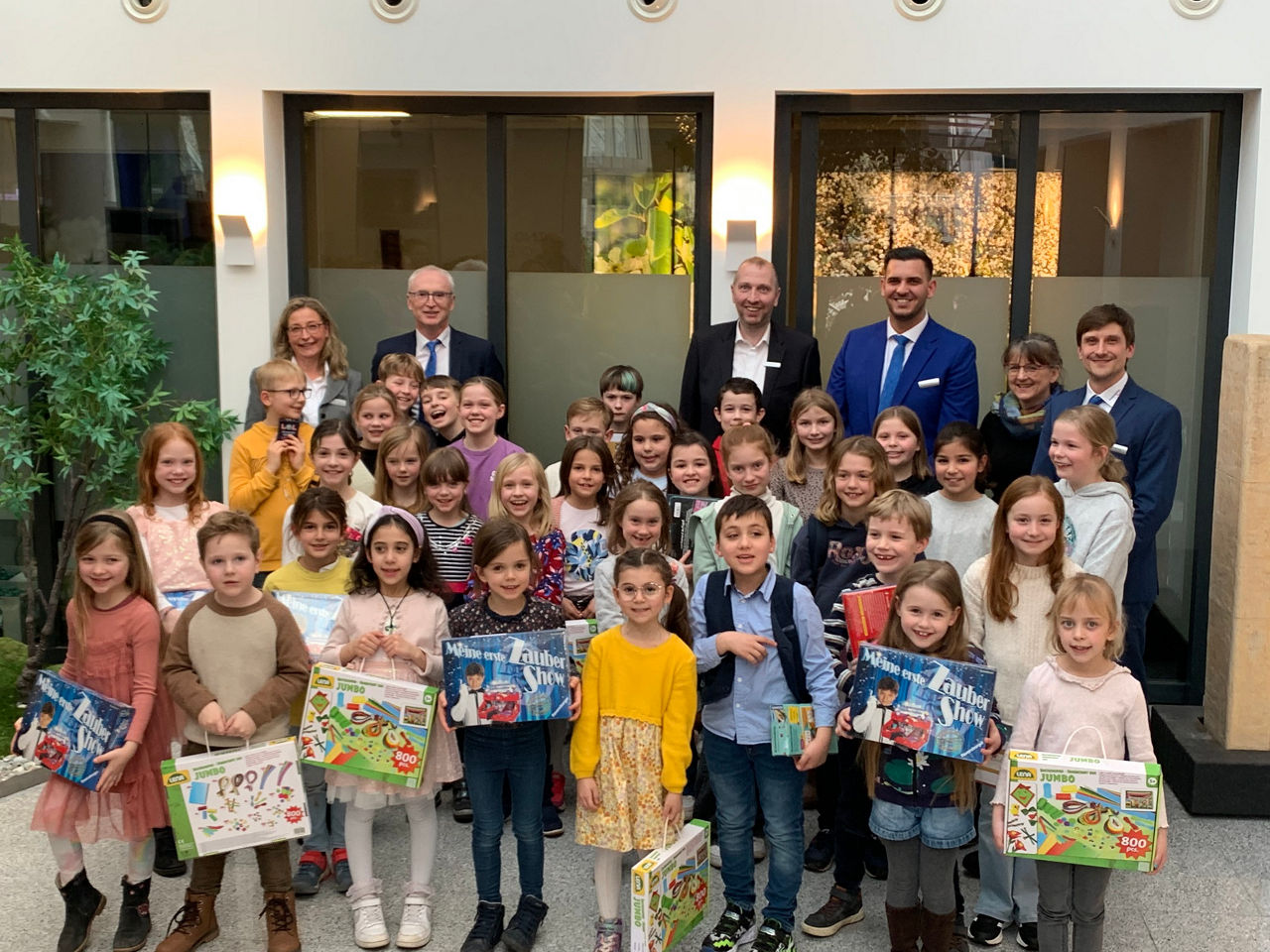 glückliche Kinder mit Geschenken in der Bank mit dem Vorstandes im Hintergrund