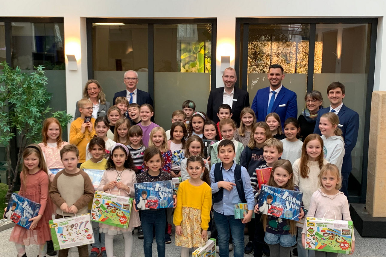 glückliche Kinder mit Geschenken in der Bank mit dem Vorstandes im Hintergrund
